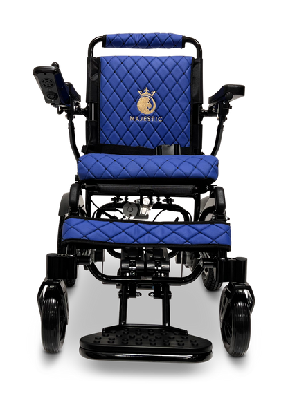 Front view of the ComfyGo MAJESTIC IQ-9000 Auto Reclining Electric Wheelchair, featuring aircraft-grade aluminum alloy, blue quilted cushions, armrests, footrest, left-side control panel, and a “Majestic” logo with crown on the backrest.