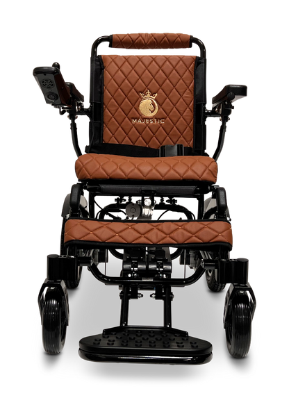 The ComfyGo MAJESTIC IQ-9000 Auto Reclining Electric Wheelchair features black aircraft-grade aluminum, rich brown quilted leather, a gold Majestic logo on the back, digital joystick controller (right armrest), and a sturdy front footrest.