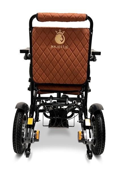 A rear view of the ComfyGo MAJESTIC IQ-9000 Auto Reclining Electric Wheelchair, brown and quilted with a black aircraft-grade aluminum alloy frame, large wheels, and Majestic plus a crown logo embroidered on the backrest.