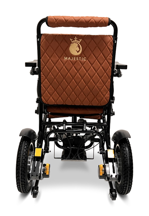 The ComfyGo MAJESTIC IQ-9000 Auto Folding Electric Wheelchair is a black foldable wheelchair that features a brown quilted backrest and seat cover, embellished with the word "Majestic" and a crown logo. It is equipped with brushless silent motors, large rear wheels, and smaller front wheels to ensure seamless mobility and comfort.