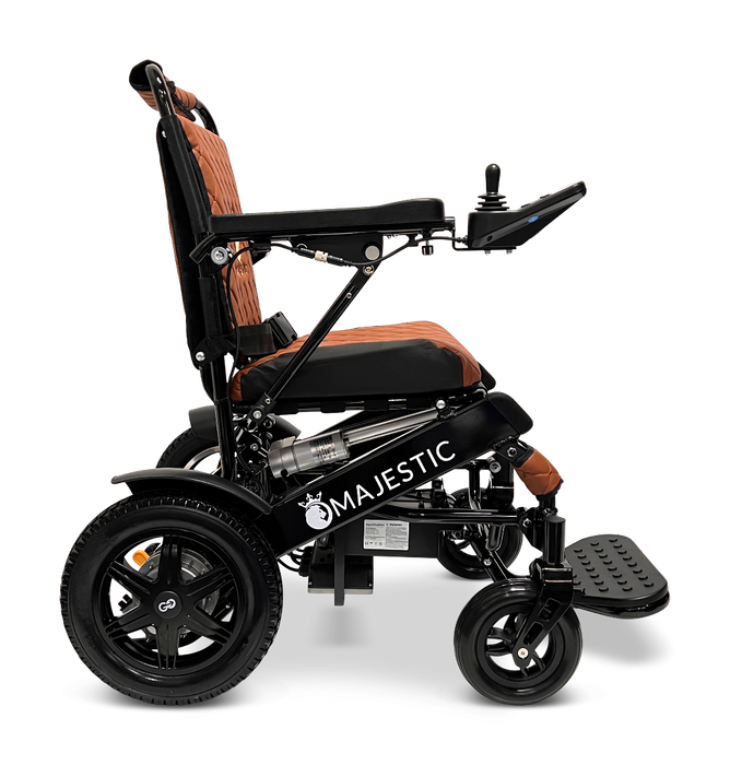 Side view of the ComfyGo MAJESTIC IQ-9000 Auto Folding Electric Wheelchair in black and orange. It includes a digital joystick controller on the right armrest, along with a cushioned seat and footrests. Powered by brushless silent motors for a smooth ride.