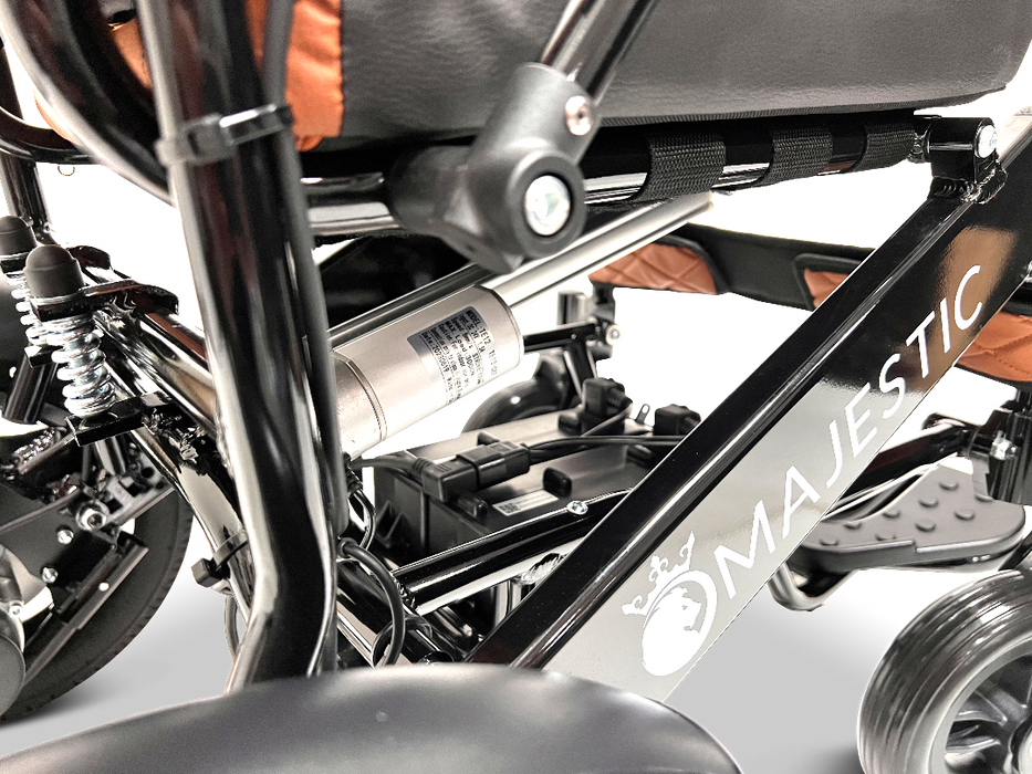 A close-up shot of the ComfyGo MAJESTIC IQ-9000 Auto Folding Electric Wheelchair highlights its intricate frame and components. The detailed image showcases features such as the suspension, wheels, and brushless silent motors, while prominently displaying the sophisticated design of the IQ-9000 AR digital joystick controller.