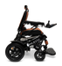 The ComfyGo MAJESTIC IQ-9000 Auto Folding Electric Wheelchair, presented in sleek black and orange, showcases a compact and modern design. It is powered by brushless silent motors for seamless operation and comes with large rear wheels. The wheelchair features an IQ-9000 AR digital joystick controller conveniently placed on the armrest and includes a practical footrest.