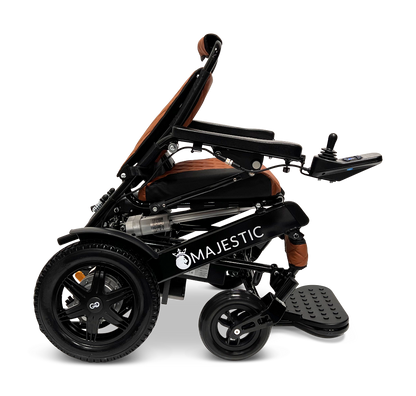 Side view of the ComfyGo MAJESTIC IQ-9000 Auto Reclining Electric Wheelchair in black and brown, featuring an aircraft-grade aluminum frame, armrests, footrest, front and rear wheels, and a right-arm digital joystick controller. Majestic appears on the frame.