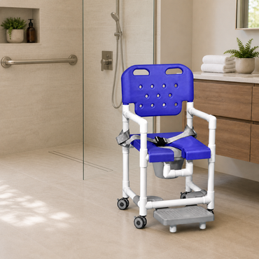 An IPU Elite PVC Rolling Shower Chair Commode with footrests, in blue and white, is positioned in a modern, accessible bathroom featuring a walk-in shower, grab bar, and a wooden vanity adorned with towels and a plant.