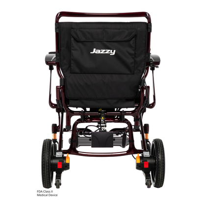 Rear view of the Pride Jazzy Carbon HD Bariatric Portable Powerchair, showing large rear wheels, smaller front wheels, Jazzy branding on the backrest, and visible mechanisms under the seat.