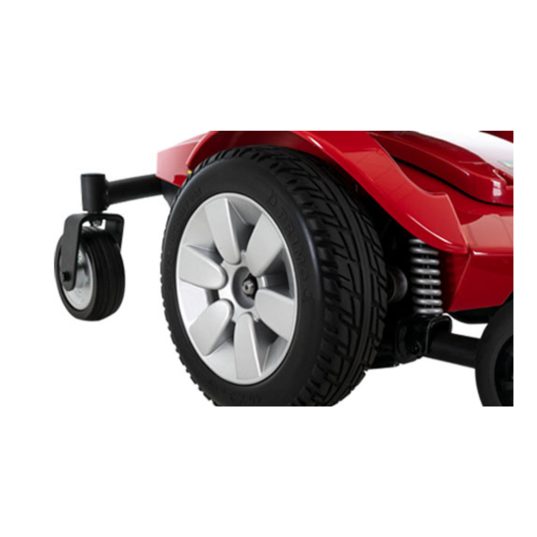 Close-up of the rear and side wheels of a red Pride Mobility Jazzy Select® Powerchair, highlighting the tire tread, suspension system, and part of the chair's frame.