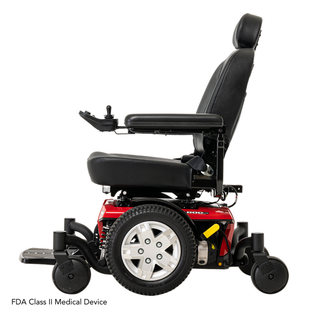 Side view of the Pride Mobility Jazzy® 600 ES Powerchair with ATX Suspension: black seat, armrests, headrest, red base, large gray wheels, left-arm joystick. Features Mid-Wheel 6® technology for top maneuverability. FDA Class II Medical Device at bottom.