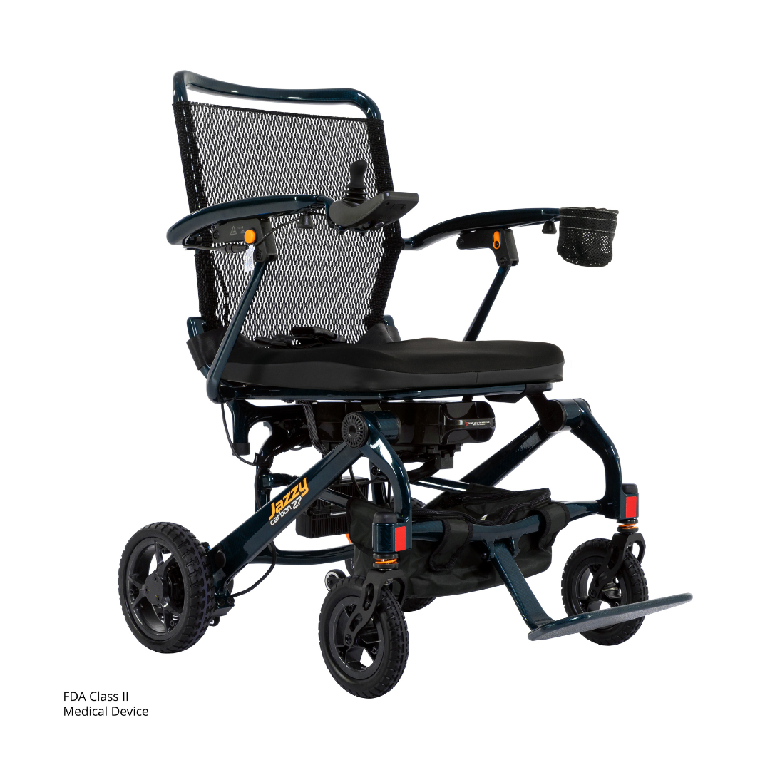 The Jazzy® Carbon 27 Ultralite Portable Power Wheelchair is a lightweight, foldable carbon fiber chair with black mesh backrest, cushioned seat, adjustable armrests, cup holder, small wheels, and visible FDA Class II medical device label.