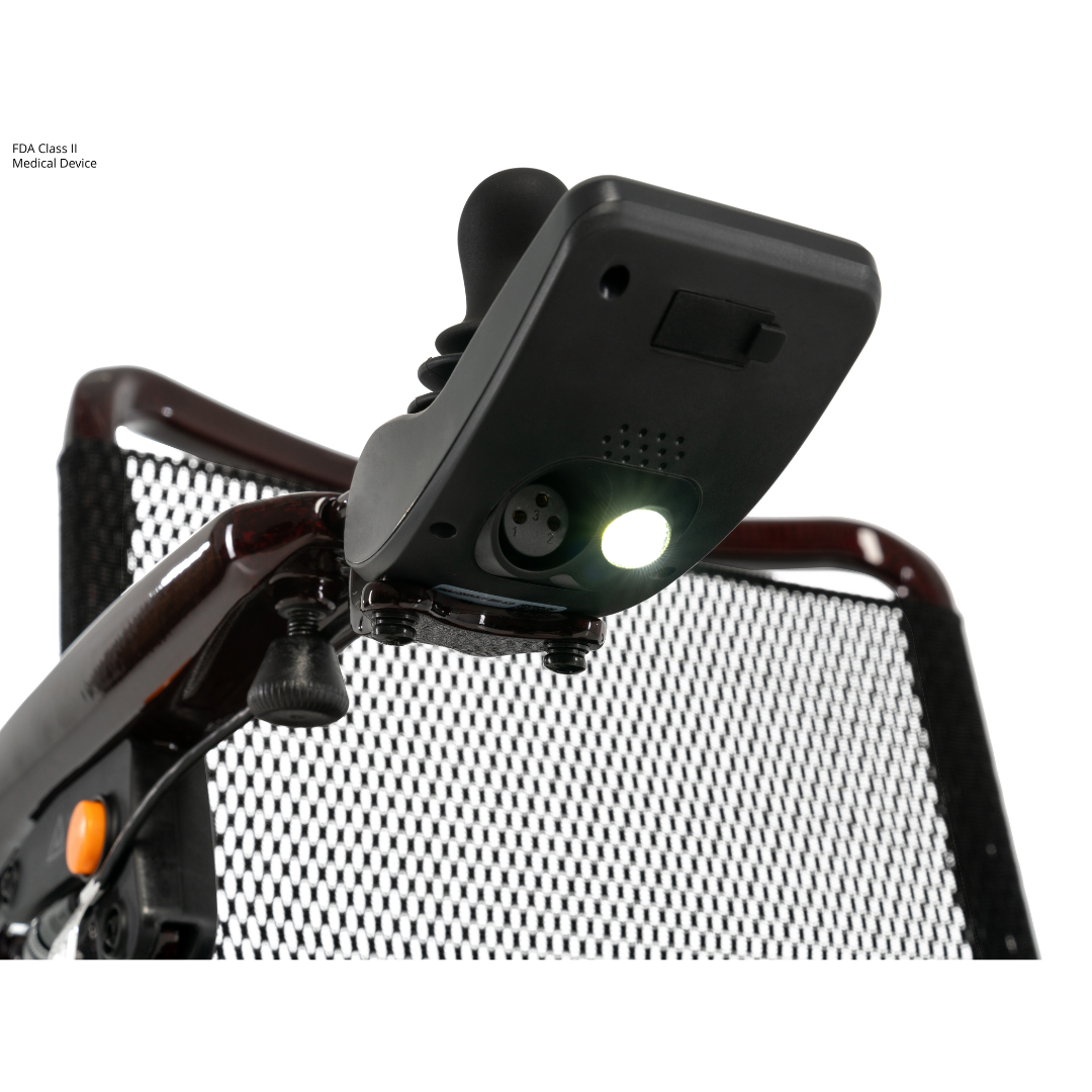 Close-up of the joystick controller attached to the armrest of the Jazzy® Carbon 27 Ultralite Portable Power Wheelchair, featuring a mesh seat back and an illuminated light beneath the controller.