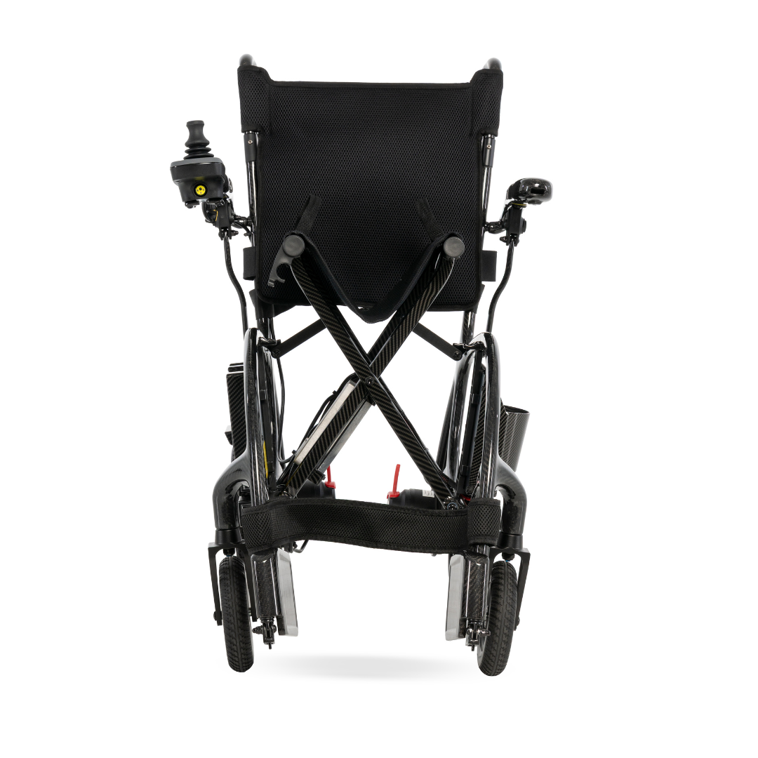 A rear view of the Pride Jazzy® Carbon 27X Portable Power Wheelchair, folded for easy transport or storage, featuring ultra-lightweight design, sturdy wheels, and a joystick controller on the left armrest.