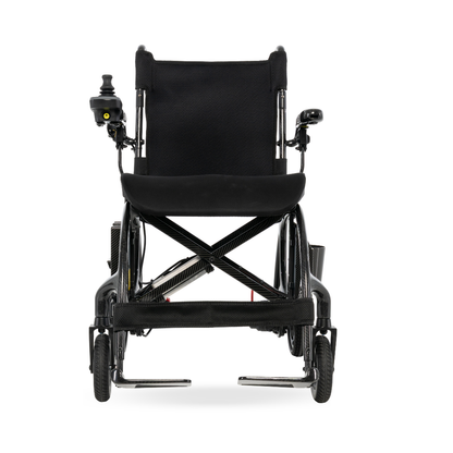 Front view of the Pride Jazzy® Carbon 27X Portable Power Wheelchair in sleek black, featuring armrests, small front wheels, a left-arm joystick control, and cushioned seat and backrest—an ultra-lightweight chair ideal for travel.