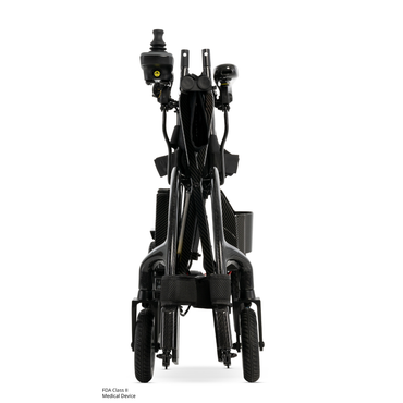 Front view of the Pride Jazzy® Carbon 27X Portable Power Wheelchair, a compact, black ultra-lightweight chair with joystick controls, small front wheels, and footrests—designed for easy transport and storage.