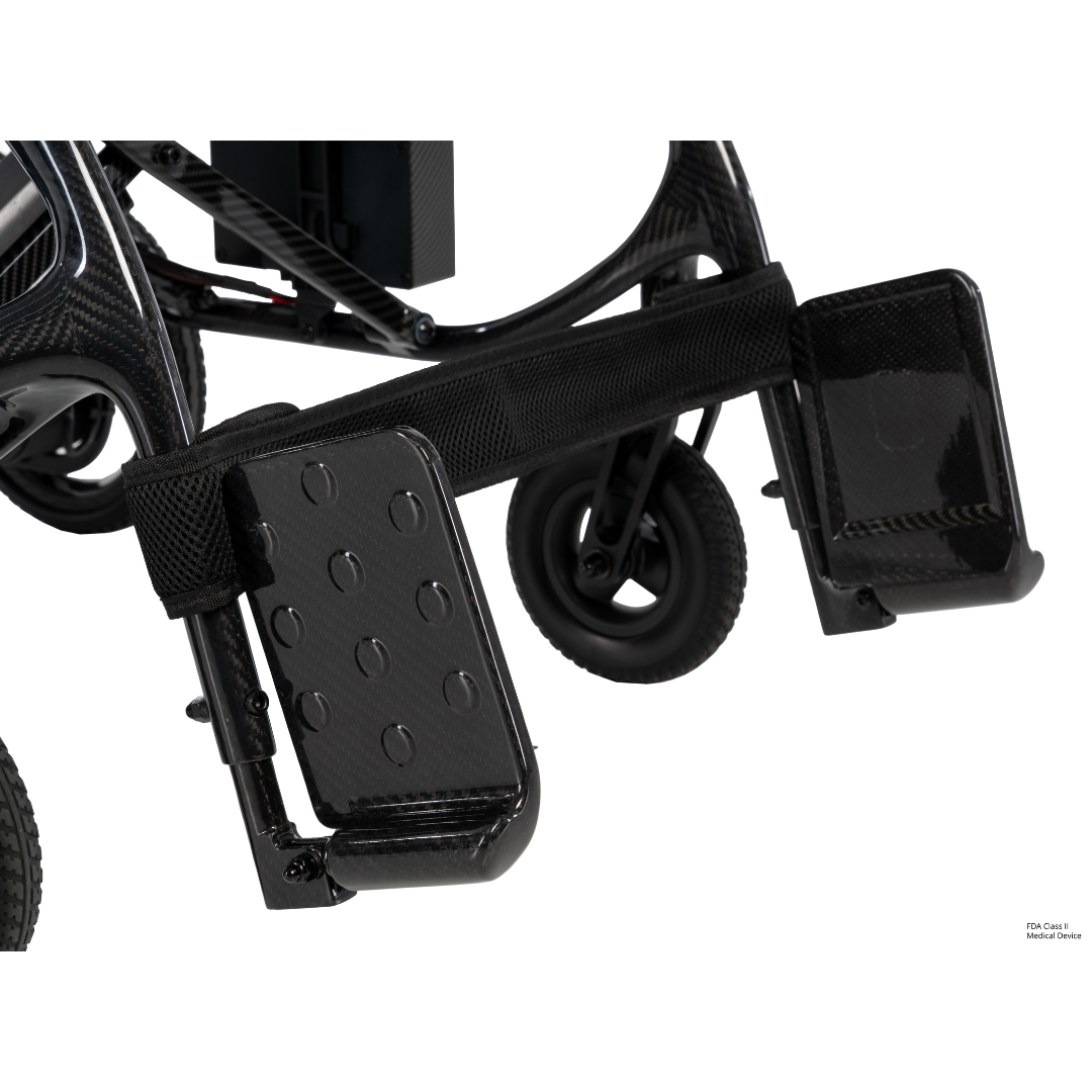 Close-up of the footrests and lower frame of the Pride Jazzy® Carbon 27X Portable Power Wheelchair, featuring textured black footplates and small front wheels on a white background.