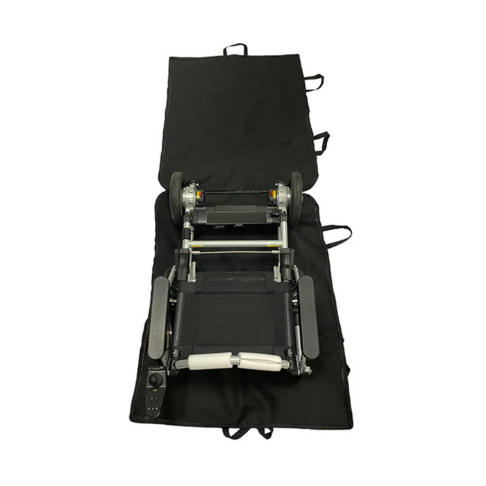 A compact, foldable electric wheelchair rests on the Journey Travel Bag with Wheels for Zinger or Zoomer Powerchairs, displaying visible straps. The mobility device has a black seat and silver frame, with a control panel on one armrest.