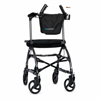 A black Journey UPWalker® Original Upright Rolling Walker Rollator featuring four wheels, a padded seat, upright arm supports, and a storage pouch attached to the front.