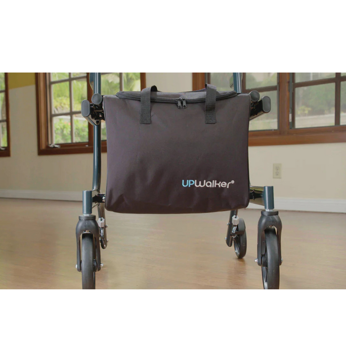 A close-up of a Journey UPWalker Parts & Accessories mobility aid indoors highlights its sleek black storage bag with the brand name. This luxury personal bag complements the UPWalker, positioned on a wooden floor, framed by windows and a beige wall.