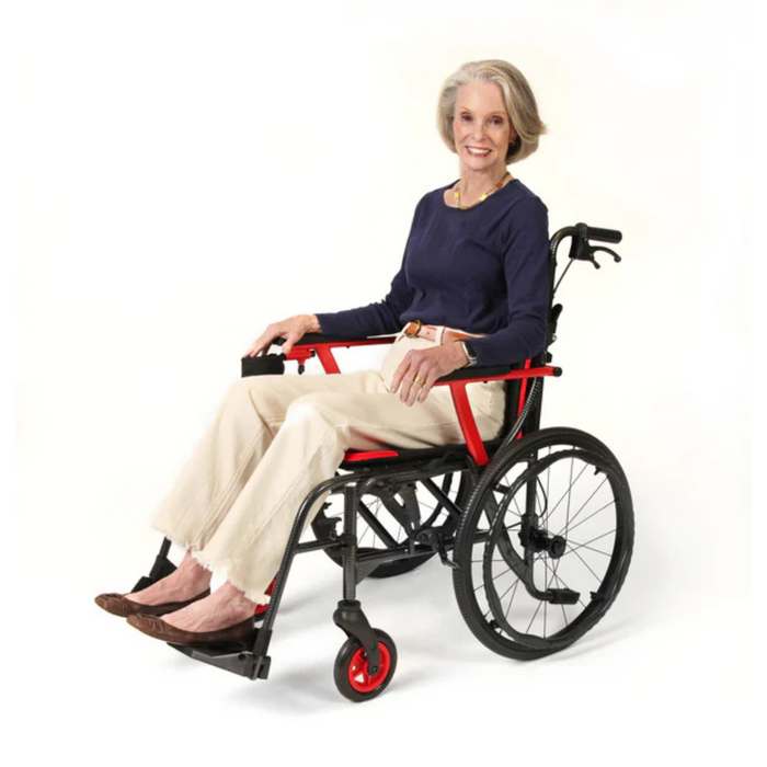 An older woman with gray hair smiles while seated in the Journey So Lite® C2 Ultra Lightweight Wheelchair. Shes wearing a navy sweater, light beige pants, and brown shoes against a plain white backdrop.