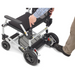 A person showcases the Journey Zoomer® Portable Travel Powerchair. The image captures hands gripping the seat and a foot pressing a lever, emphasizing its maneuverability and compact design. Its FAA approved, epitomizing portable mobility and modern convenience in travel.