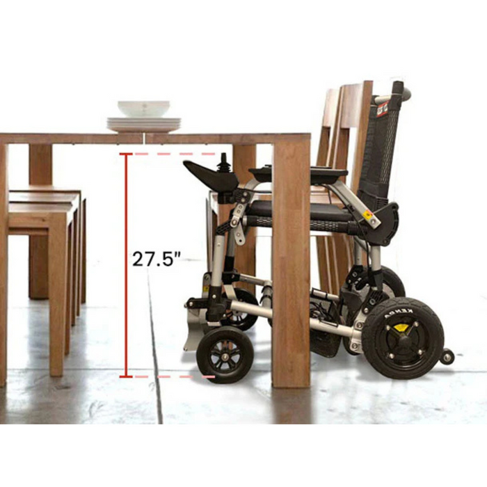 The Journey Zoomer® Portable Travel Powerchair, FAA Approved, is compactly folded beside a dining table. Its innovative design and 27.5-inch height allow it to fit easily under the table.