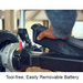 A person removes the battery from a Journey Zoomer® Portable Travel Powerchair - FAA Approved, highlighting its tool-free, easily removable design. The indoor setting emphasizes portable mobility with a clear view of the rear wheel and battery compartment.