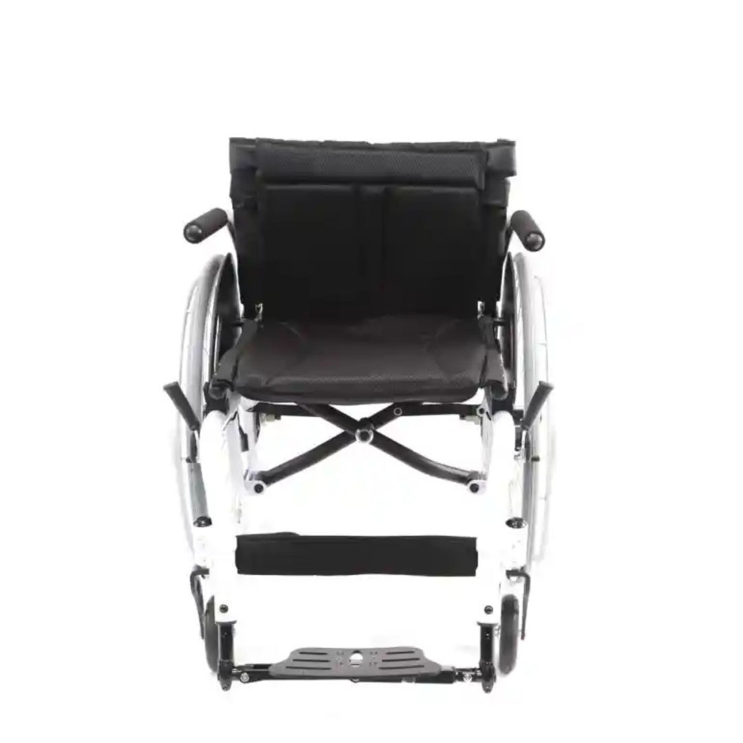 A front view of the foldable Karman S-Ergo ATX Active Wheelchair, in silver and black against a white background, showcases its ergonomic design with a black fabric backrest and seat. Visible armrests and footrests highlight the ultralite models impressive strength-to-weight ratio at just 26 lbs.