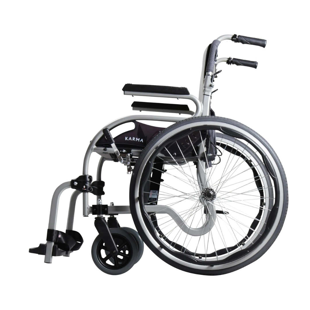 The Karman Healthcare STAR 2 Lightweight Folding Wheelchair has an ergonomic design with large rear wheels, small front casters, footrests, padded armrests, and a silver frame with black accents displaying Karma on the side.