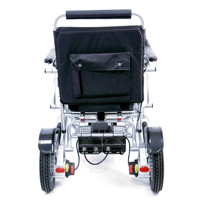 Rear view of the Karman Tranzit Foldable Lightweight Power Wheelchair in black, designed as a compact mobility device. It has large textured wheels, a padded handlebar, storage pocket on the backrest, and visible cables and electronics beneath the seat. FAA approved for air travel.