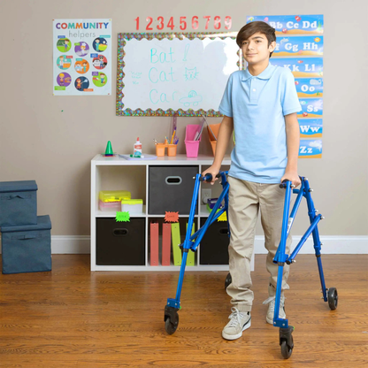 A boy uses the Circle Specialty Klip Pediatric Posterior Walker in a classroom with a whiteboard showing words like Bat, Cat, and Car. Colorful posters and storage bins are visible in the background.