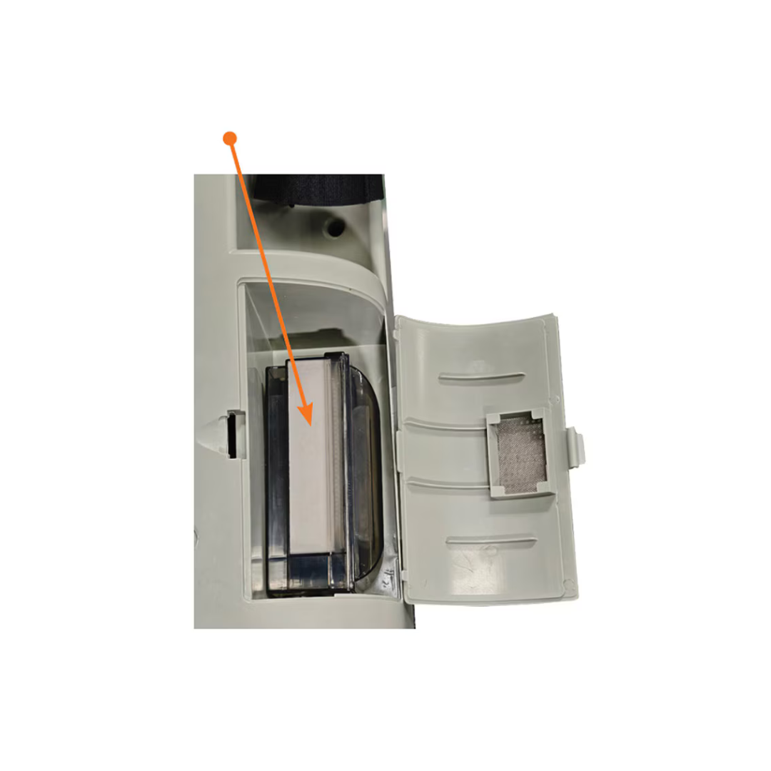 Close-up of an open appliance compartment with a filter exposed—an orange arrow points to the rectangular filter inside the gray plastic housing, highlighting one of the essential components included in Accessoires For Rhythm LM10A O2 Concentrators.