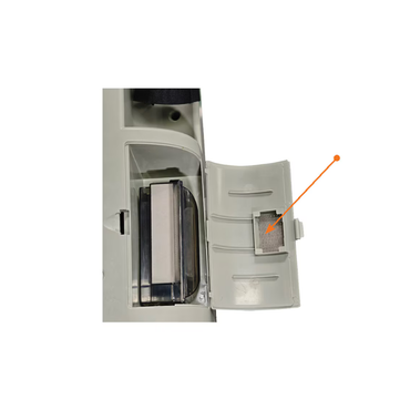 A close-up of an open compartment with an orange arrow pointing to a small rectangular mesh filter inside the door, which is part of the Accessoires For Rhythm LM10A O2 Concentrators. This filter is a crucial oxygen concentrator part that helps maintain optimal performance.