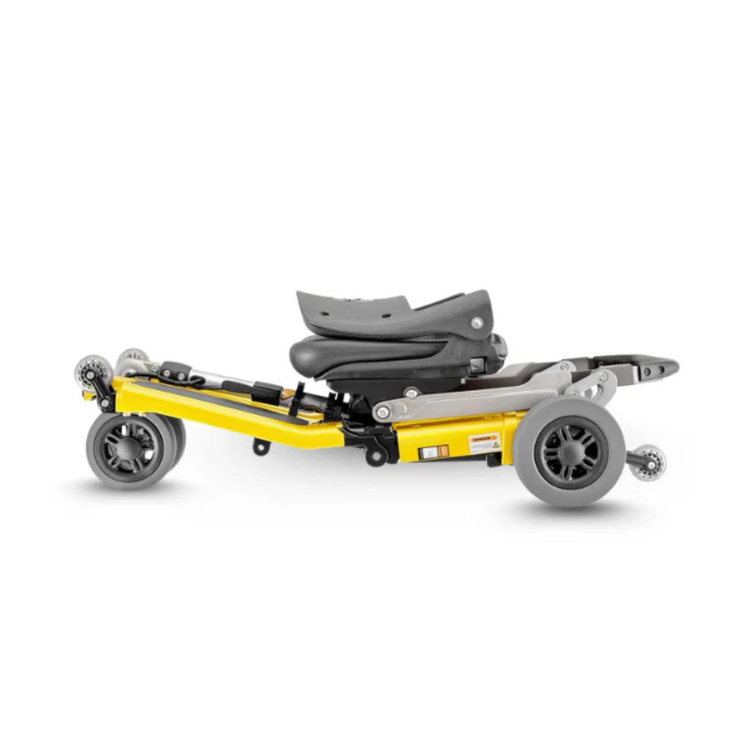 The FreeRider Luggie Standard Travel Scooter is a compact, lightweight foldable scooter in yellow and black with gray wheels, shown fully collapsed for easy transport and storage—ideal for travel mobility.