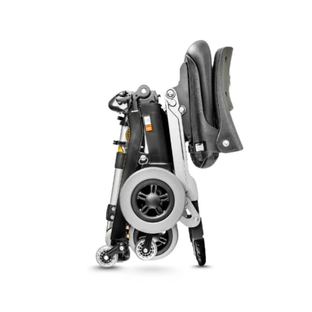 The FreeRider Luggie Standard Travel Scooter is a compact, portable mobility aid with large rear wheels and small front casters. Shown upright against a white background, its seat and frame are neatly folded to save space.
