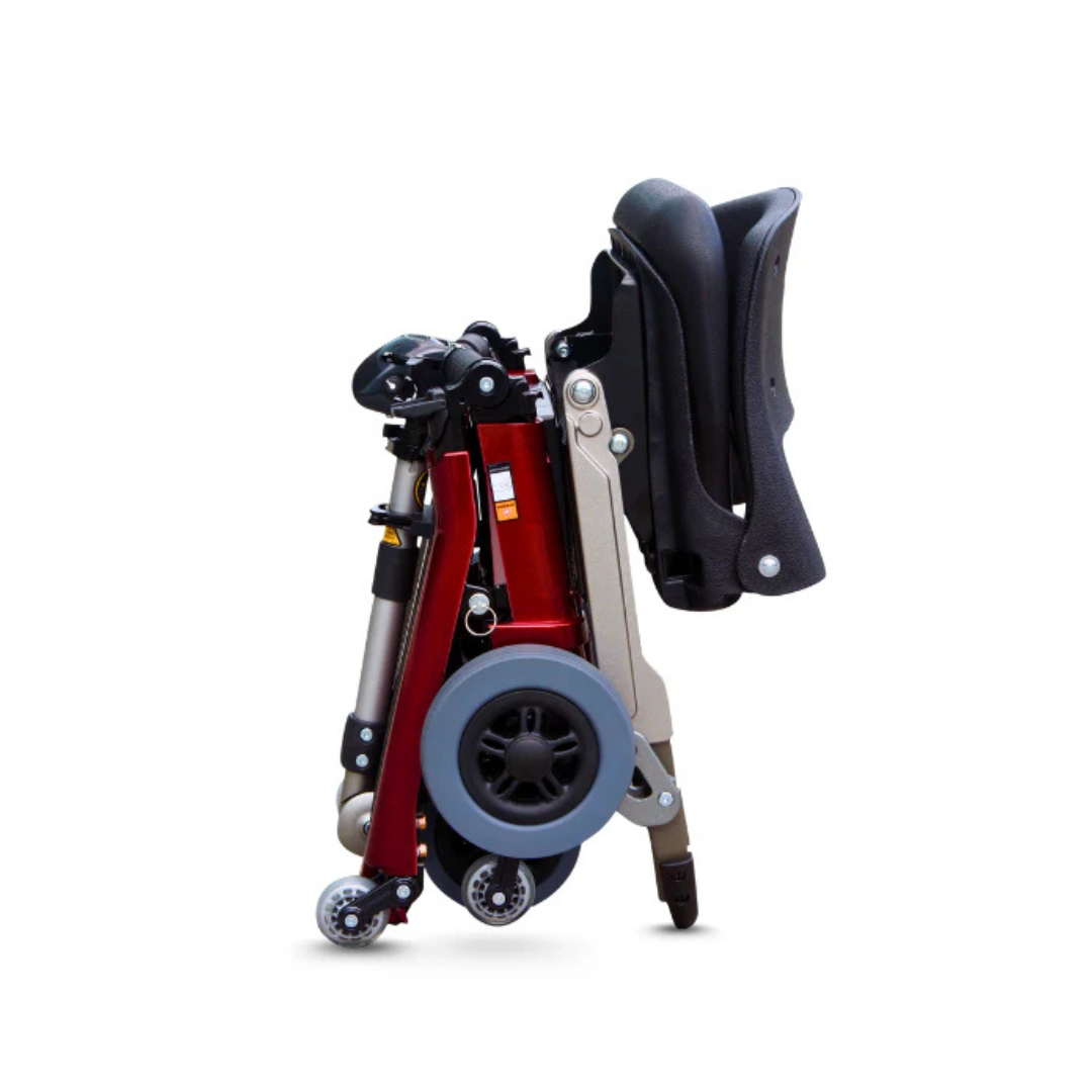 The FreeRider Luggie Standard Travel Scooter, shown fully folded in red and black with large and small wheels visible, highlights its compact travel mobility features against a plain white background.