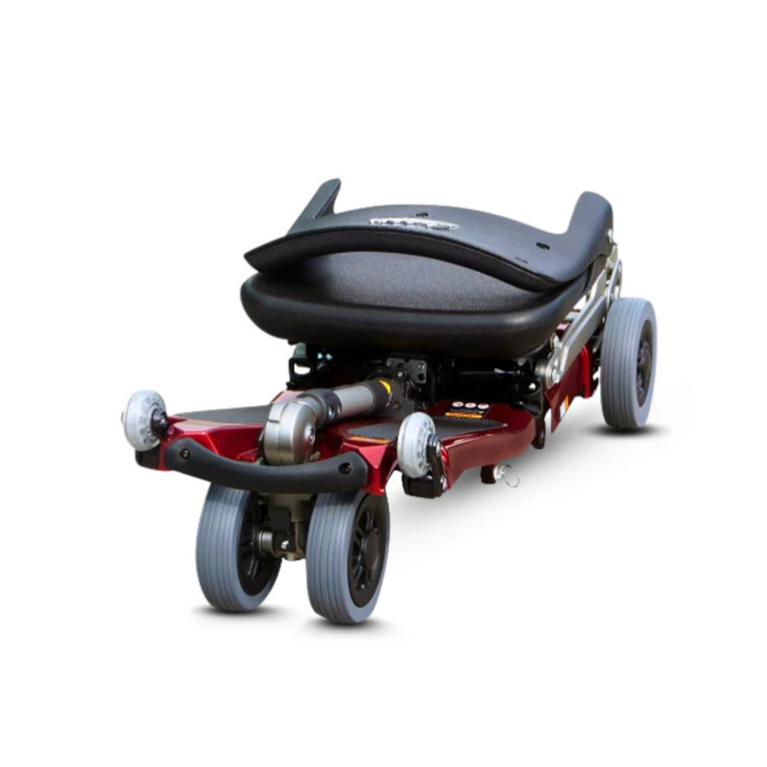 The FreeRider Luggie Standard Travel Scooter is a compact, lightweight foldable scooter with a black seat, red frame, and four small wheels, ideal for portable mobility. Shown against a white background.