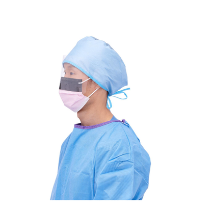 A person in profile wears blue scrubs, a matching cap, and a Medline ASTM L3 Procedure Face Mask with Eye Shield and Ear Loops, standing against a plain white background.