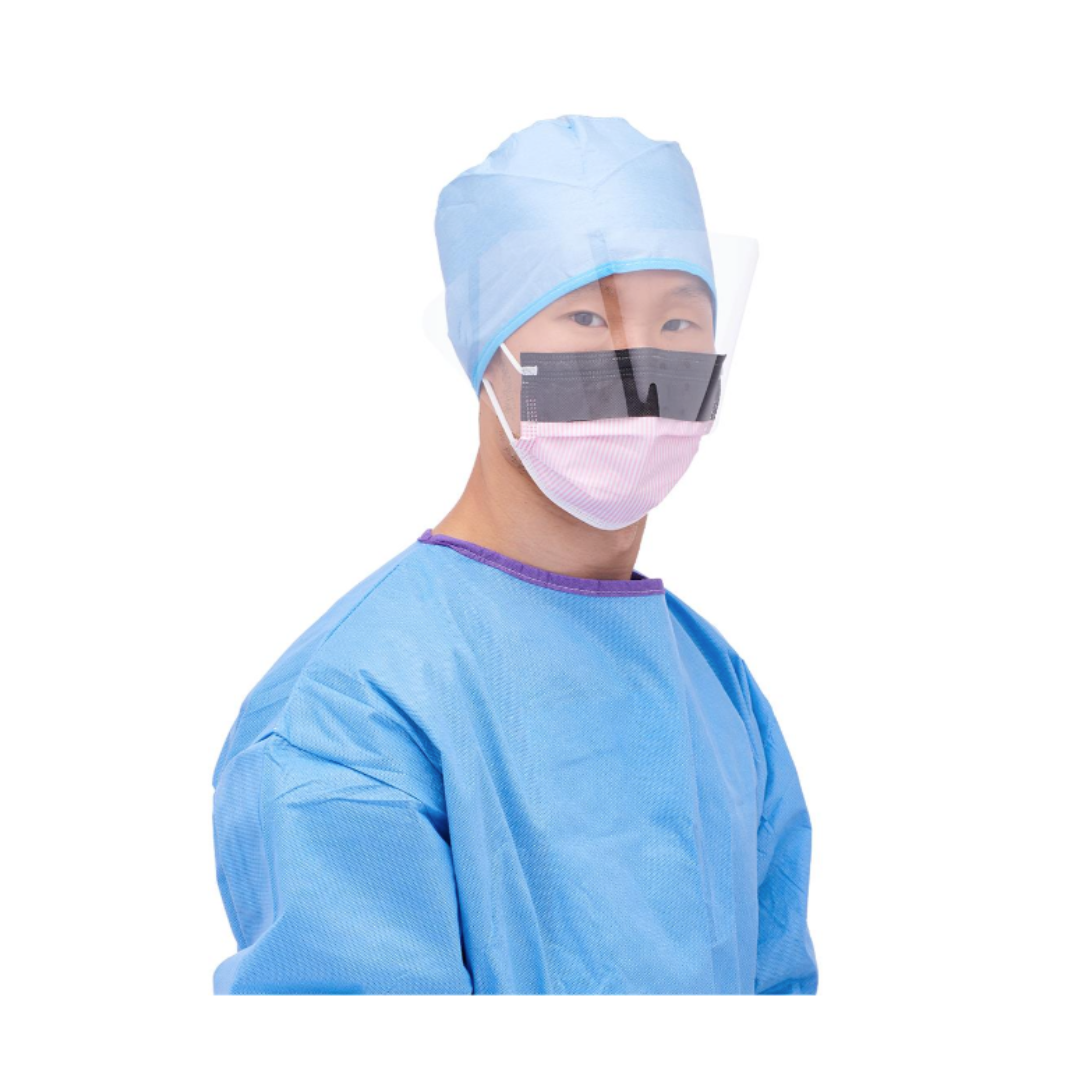 A person in blue scrubs and cap wears a Medline ASTM L3 Procedure Face Mask with Eye Shield and Ear Loops, looking toward the camera against a white background.