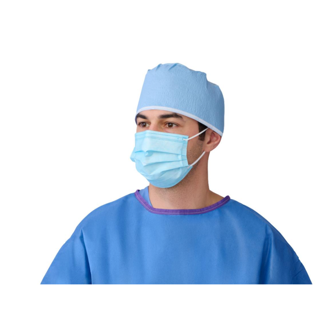 A person in a blue surgical gown and light blue cap wears a Medline ASTM Level 3 Procedure Face Mask with Ear Loops, looking slightly to the side against a white background.