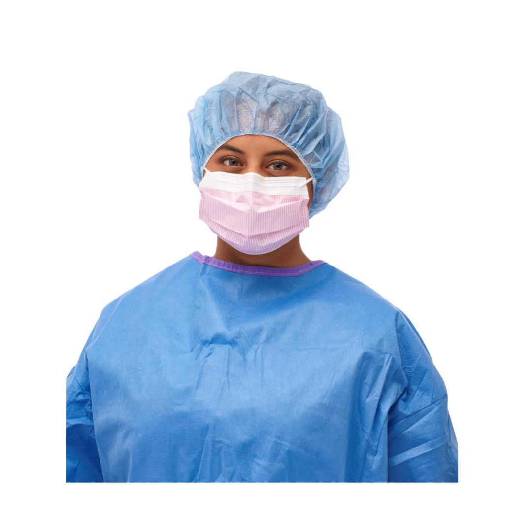 A person in a blue surgical gown, blue hair cap, and a pink Medline ASTM Level 3 Procedure Face Mask with ear loops stands against a white background.