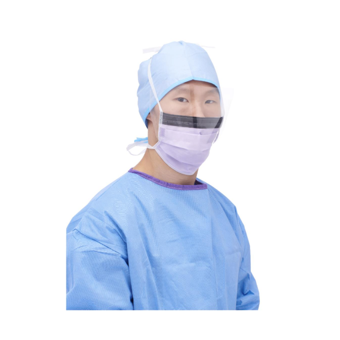 A person wearing a blue surgical gown, cap, and Medline ASTM Level 3 Surgical Face Mask with Eye Shield faces the camera against a white background.