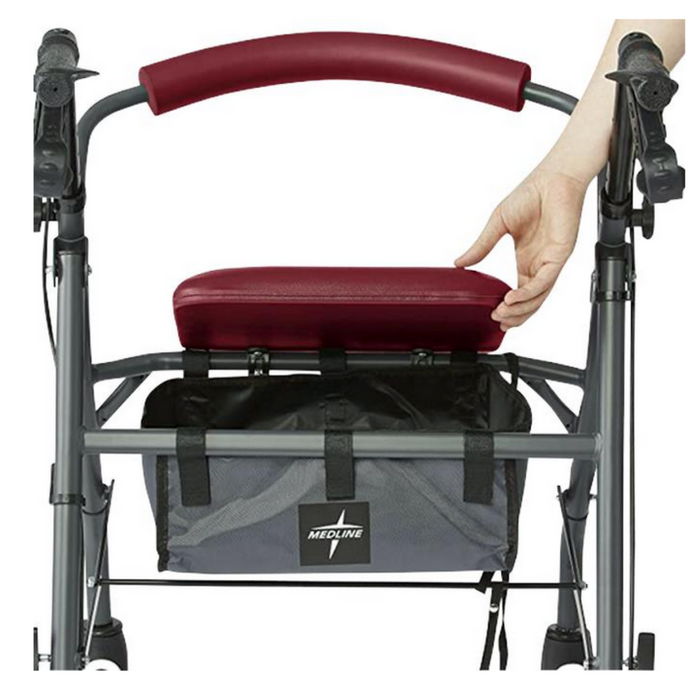 A person lifts the seat of a Medline Steel Rollator with Microban, featuring a burgundy cushion and handle. A mesh storage bag underneath displays a logo. This mobility aid has hand brakes on the handles, ensuring user safety and convenience.
