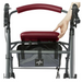A person lifts the seat of a Medline Steel Rollator with Microban, featuring a burgundy cushion and handle. A mesh storage bag underneath displays a logo. This mobility aid has hand brakes on the handles, ensuring user safety and convenience.