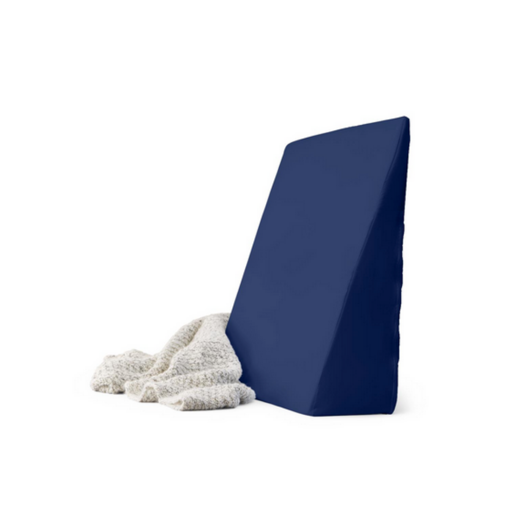 The Medline High-Density Foam Bed Wedge (24 x 20 x 8.5) in navy blue stands upright beside a light gray textured blanket on a white background.