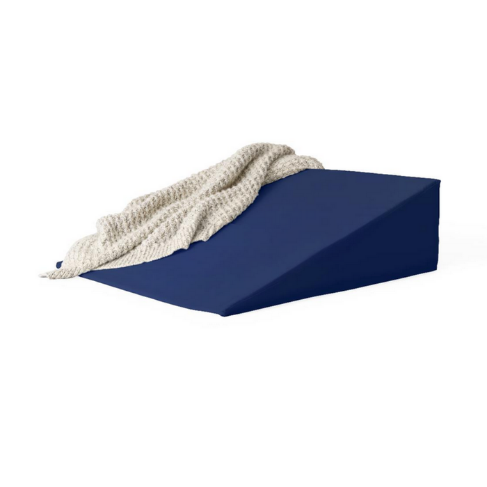 The Medline High-Density Foam Bed Wedge (24 x 20 x 8.5) in blue is shown with a textured, light beige blanket draped over one side, set against a white background.