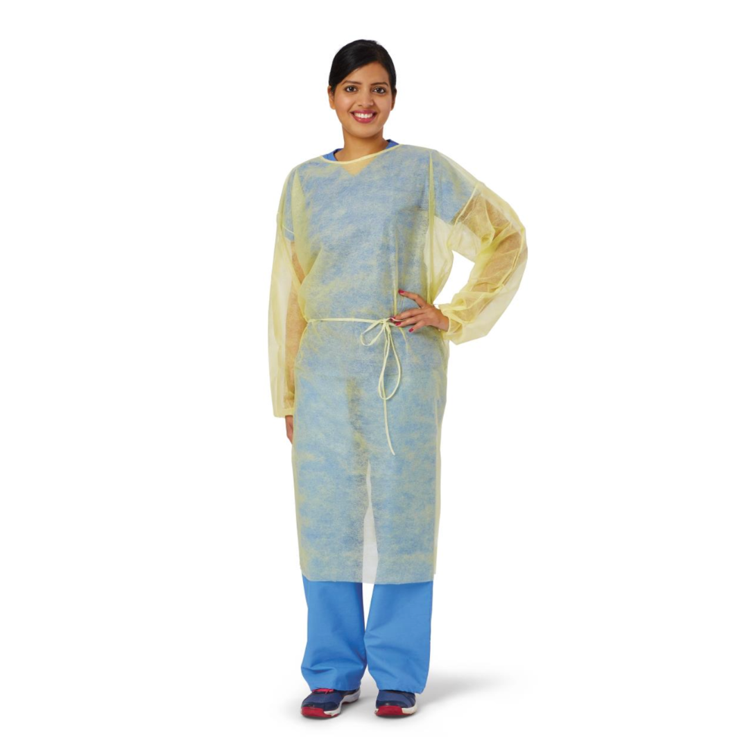 A person wearing a yellow Medline Disposable Full Back Spunbond Cover Gown over blue scrubs and black shoes stands smiling with one hand on their hip against a white background.