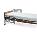 The Medline Bed Rails for Medline Homecare Beds provide patient safety, featuring sturdy metal rails, a thin white mattress, a wooden headboard, and wheels on one end for easy mobility and installation.