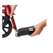 Close-up of hands adjusting the footrest on a red Medline Basic Aluminum Transport Chair with fixed full-length armrests. One hand grips the frame, while the other fine-tunes the black footrest, highlighting this durable mobility aid. A wheel is visible in the background, showing its practicality and ease of use.