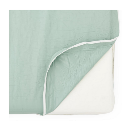 A pastel green, crinkled fitted sheet with a white elastic edge is partially pulled back to reveal the Medline Premium Foam Homecare Mattress, sized 36” x 80” x 6”, offering extra protection and comfort for your bed.
