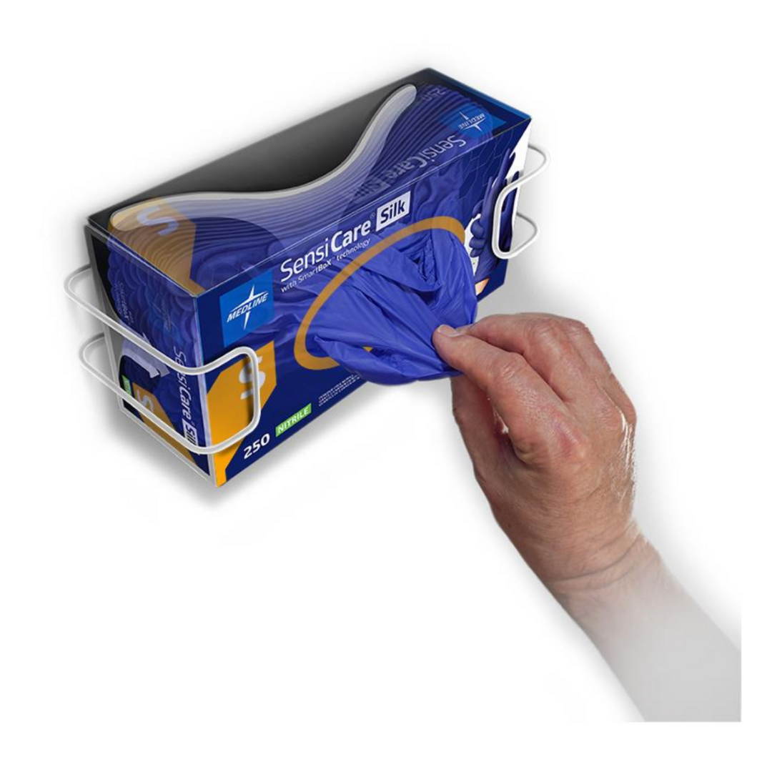 A hand pulls a blue Medline SensiCare Silk Nitrile Exam Glove with SmartBoX Design from a box mounted on a wall dispenser.