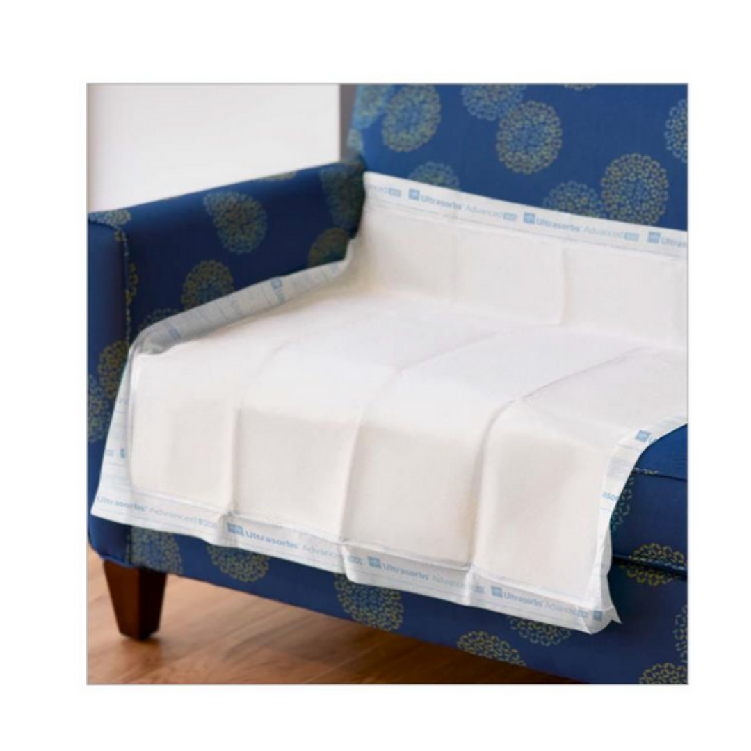 A Medline Ultrasorbs Advanced Premium Underpad (30 x 36) is spread over a blue patterned armchair, covering the seat and armrests to protect the upholstery—ideal for managing incontinence on wooden floors.